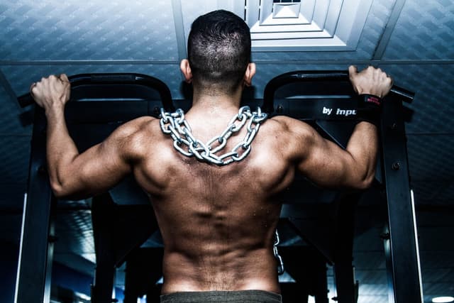 Man doing pull ups with chain around neck