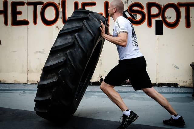 Man picking up tractor tire